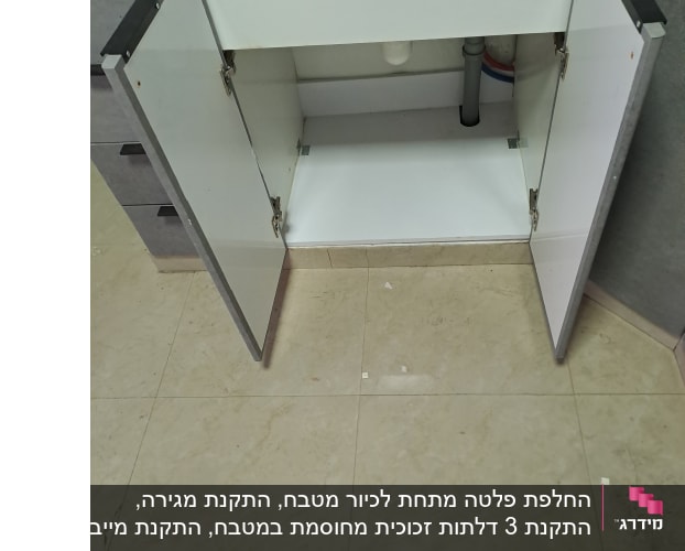 ארון מטבח פתוח עם דלתות פתוחות וצנרת גלויה מתחת לכיור